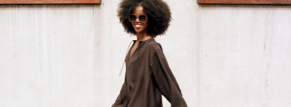Model som går på gaden i en brun maxi kjole og solbriller