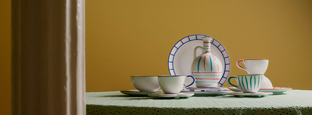 Der står keramikkopper, en tallerken og en vase på et bord. Det er fra Jore Copenhagen.