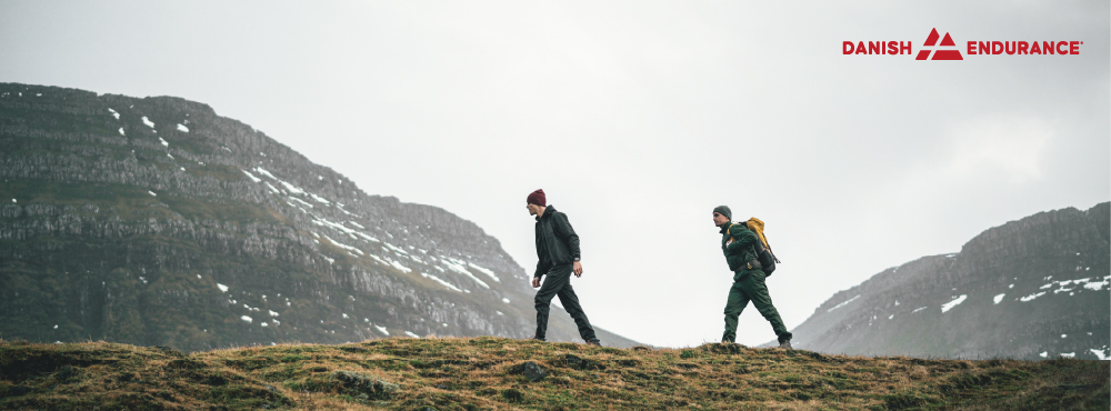 To mennesker vandrer i bjerge. De har ustyr på fra Danish Endurance.