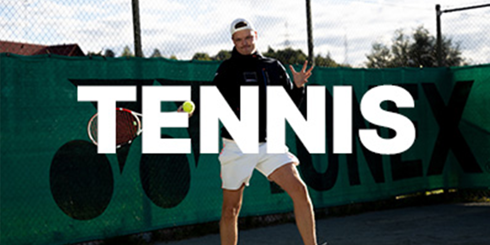 En mand står i træningstøj med en tennisketcher i hånden. Foran ham står der med blokbogstaver: Tennis.