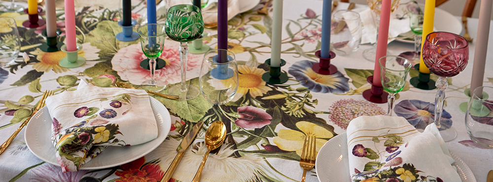 Et bord med tallerkner og stearinlys i forskellige farver fra Koustrup & Co.